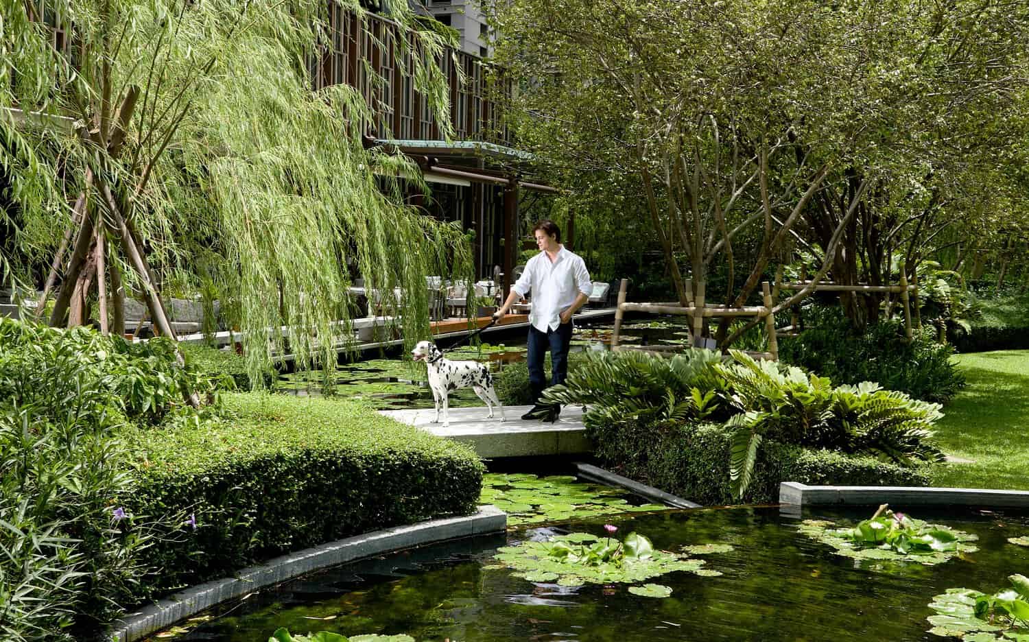 An owner and his dog inside the lush gardens of Kimpton Maa-Lai Bangkok