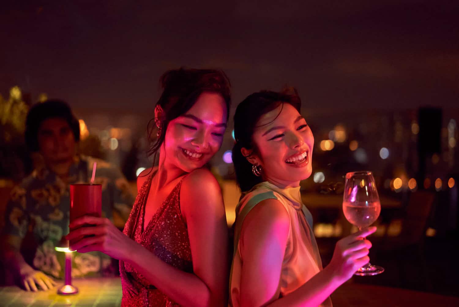 Two friends toasting and enjoying rooftop party in Bangkok