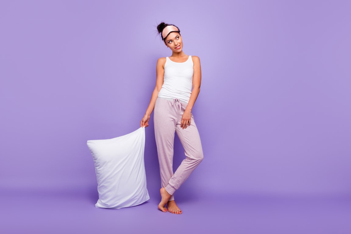 femme en pyjama sur son lit avec son oreiller