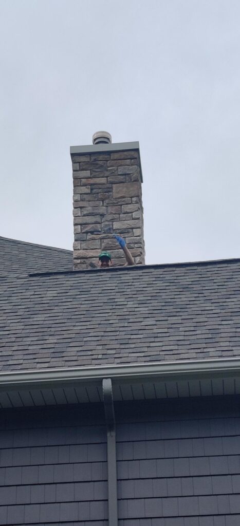 One of our technicians peaking over the rig of a house roof while providing one of our pest control services.