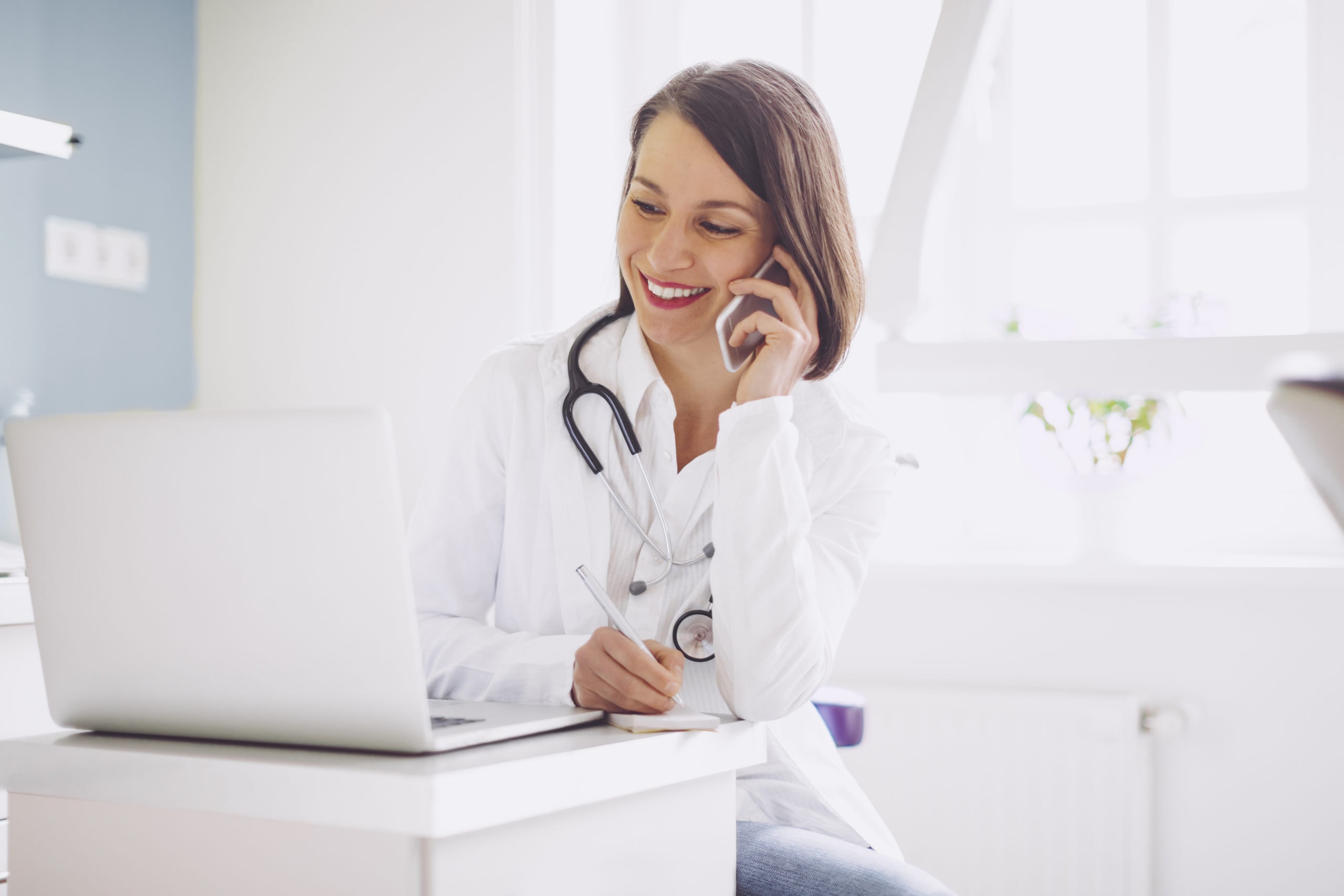 Doctor making a call in a bright, modern office setting. Doctor making a professional sales voicemail call for healthcare or medical services.