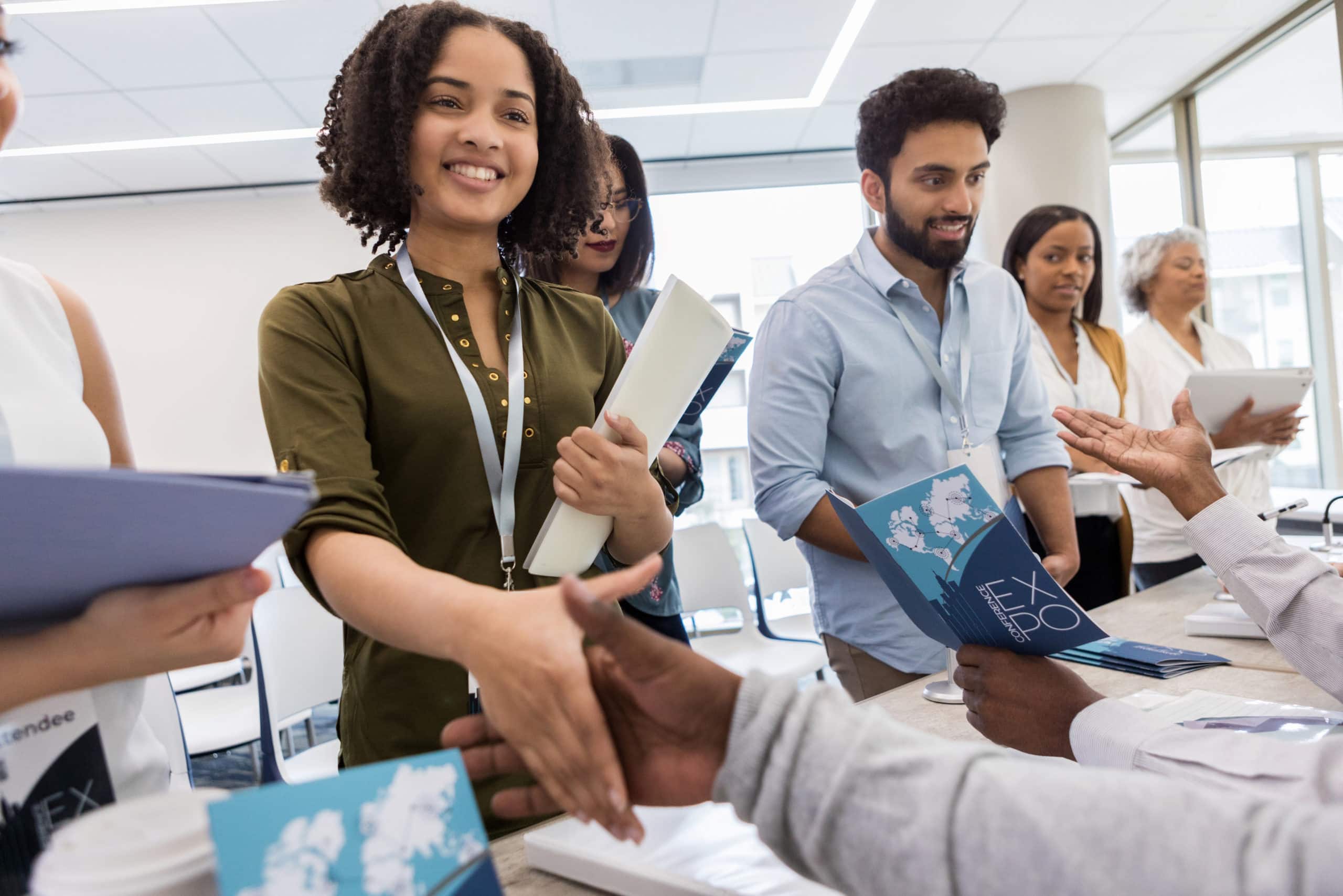 Business networking at industry event disrupted by coronavirus fears Group of diverse professionals shaking hands at a conference, pandemic impact evident.