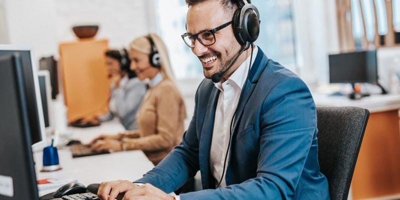 Support agent wearing headset working at computer in call center.