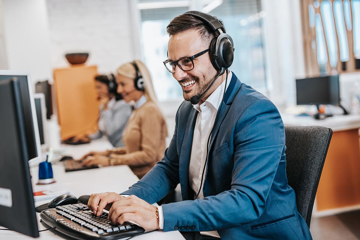 Customer support representative at a call center Support agent wearing headset working at computer in call center.