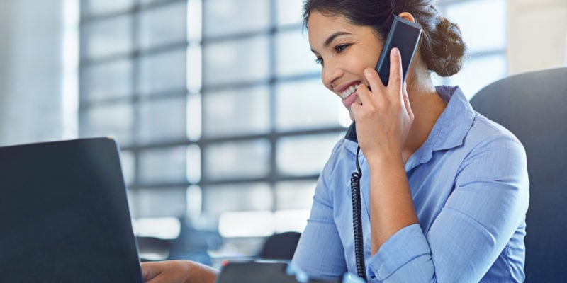 Businesswoman making a warm sales call with a headset in an office setting.