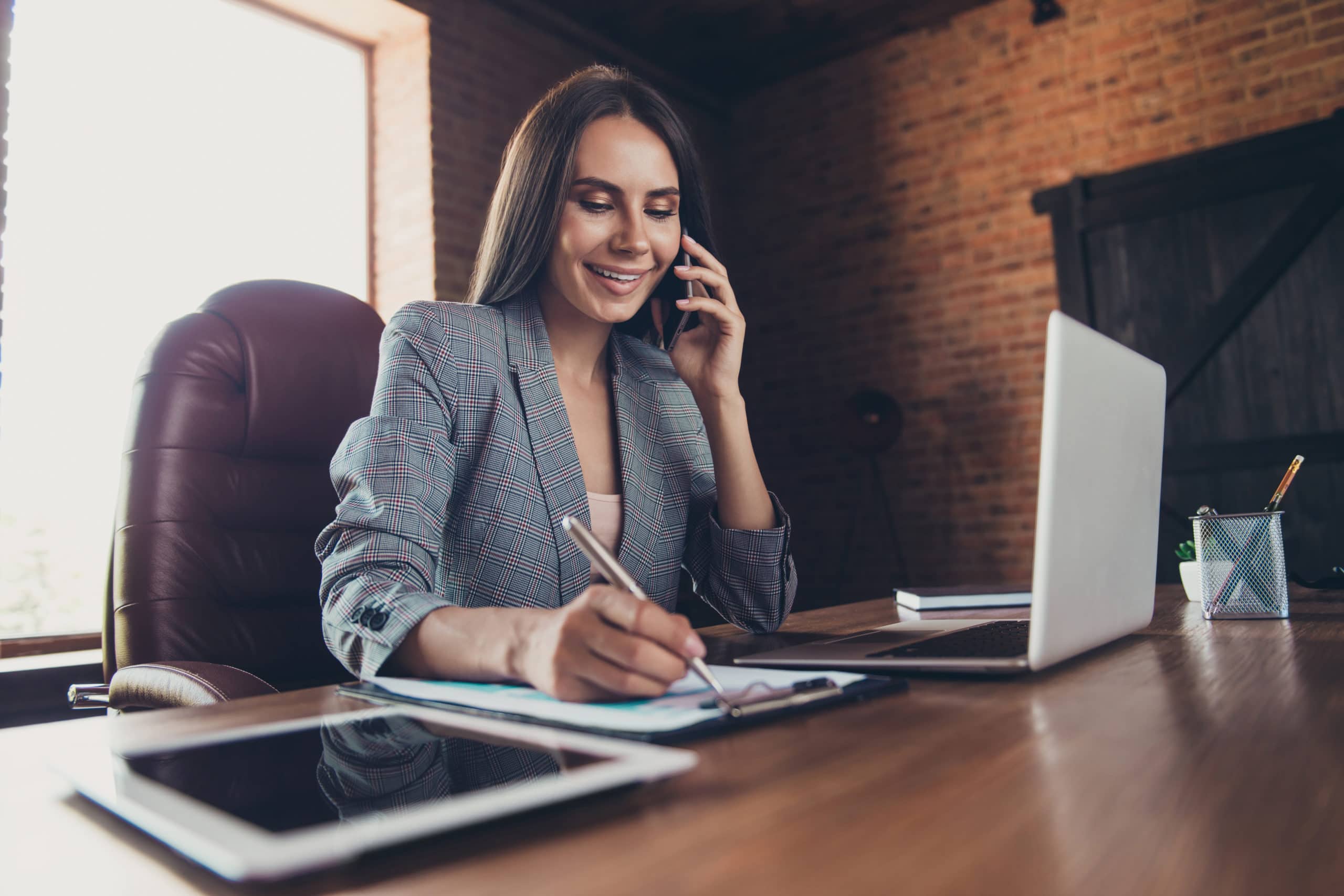 Boost Your Prospect Lists with Best Practices Businesswoman managing prospect lists on phone and laptop in modern office.
