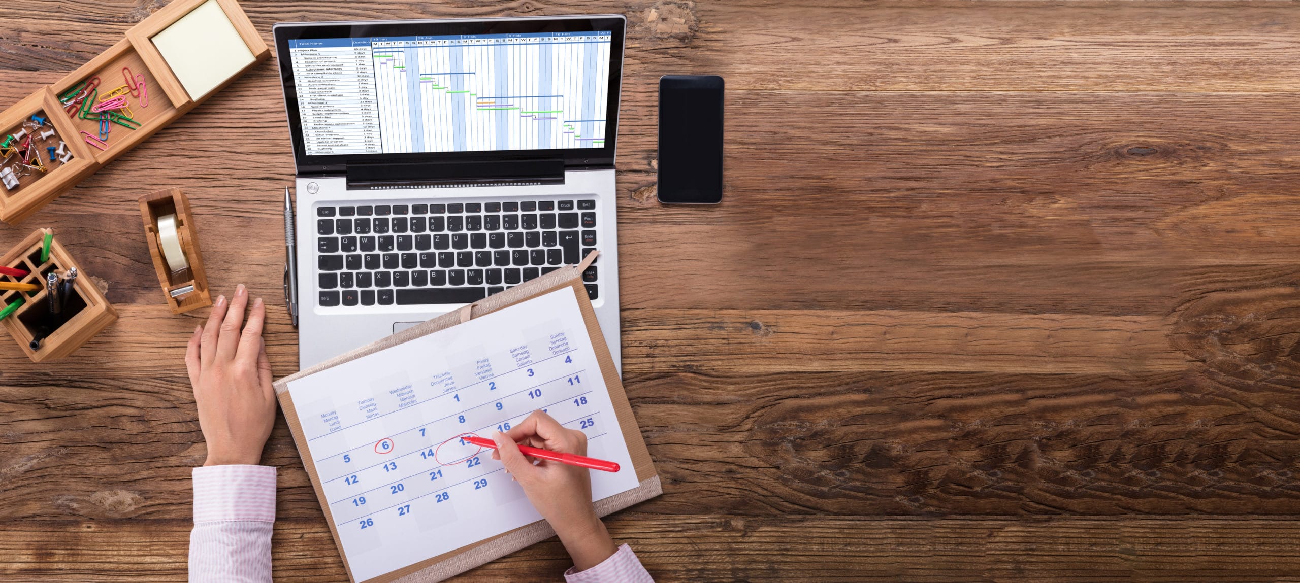 Sales team appointment setting analysis for outsourcing success Business professional reviewing sales appointment schedule on laptop and calendar.