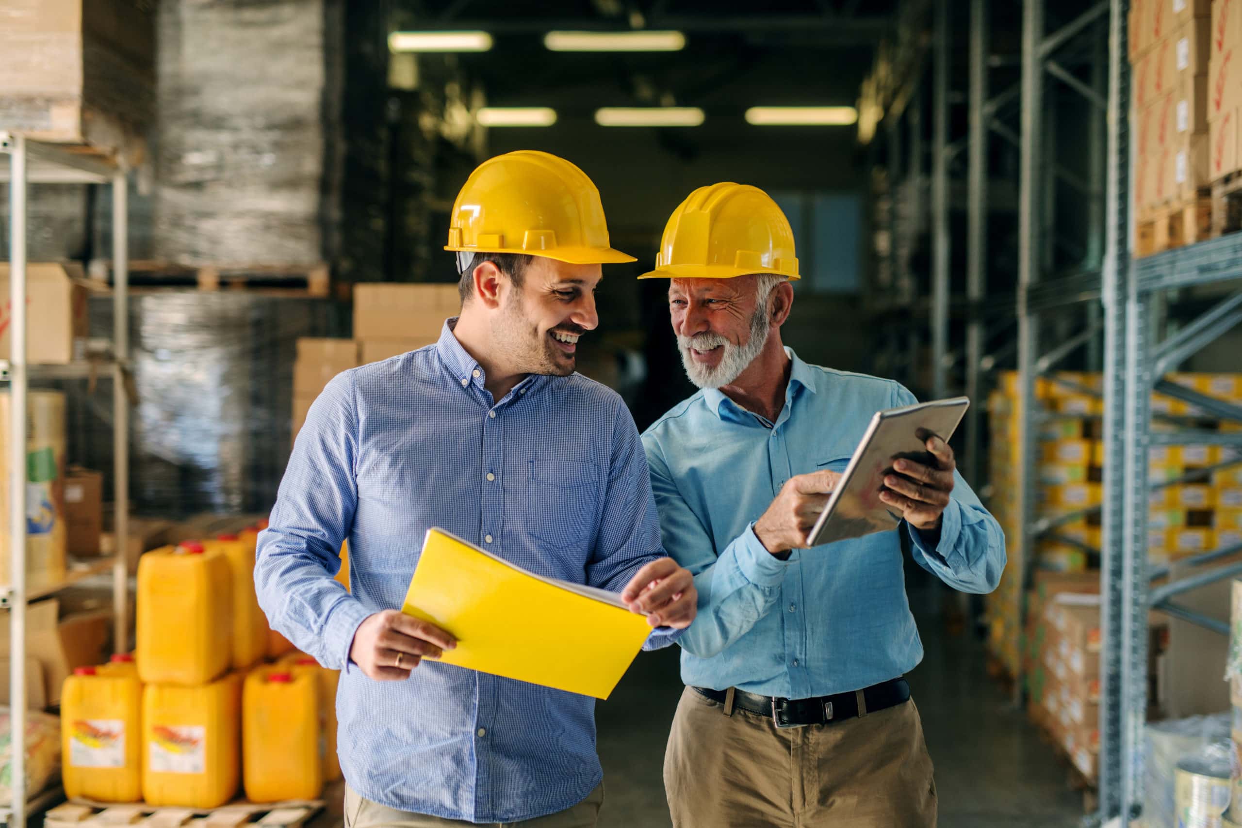 Manufacturing Success Stories Two factory managers discussing production in a warehouse.