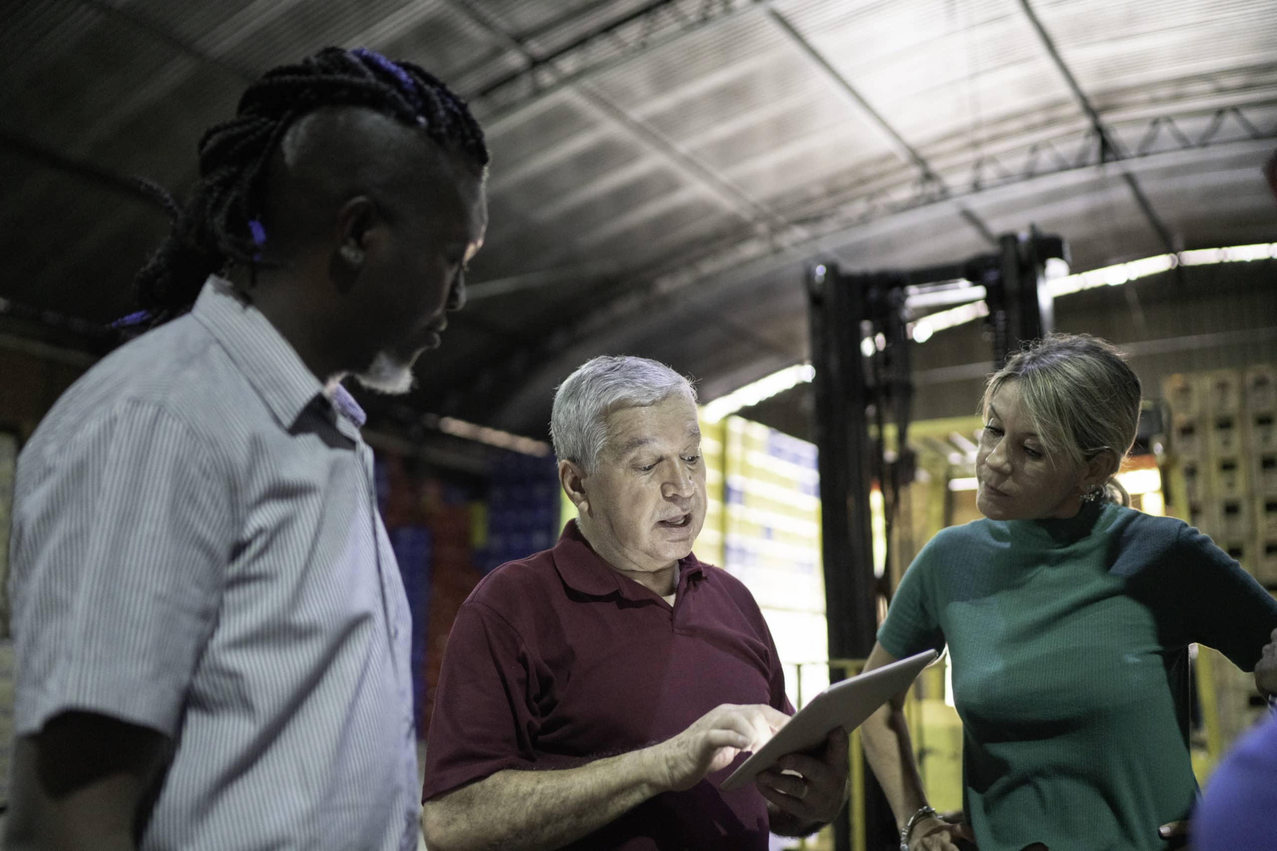 Manufacturing team discussing outbound calling strategies Manufacturing team discussing outbound calling benefits in a warehouse setting.