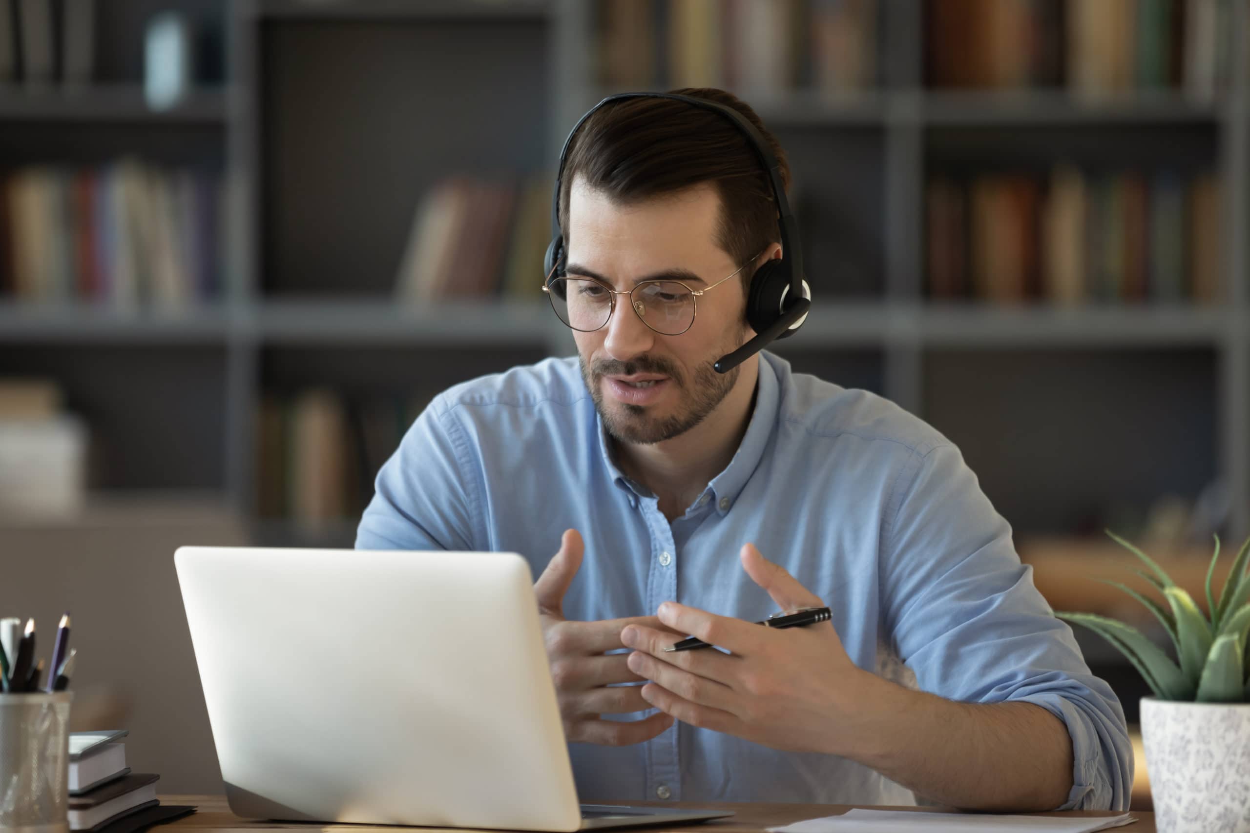 Voice of Customer Insights in B2B Sales Man with headset analyzing customer feedback on laptop in office setting.