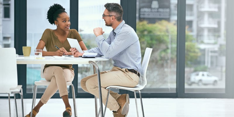 Business professionals engaging in a sales mentoring discussion in a modern office.