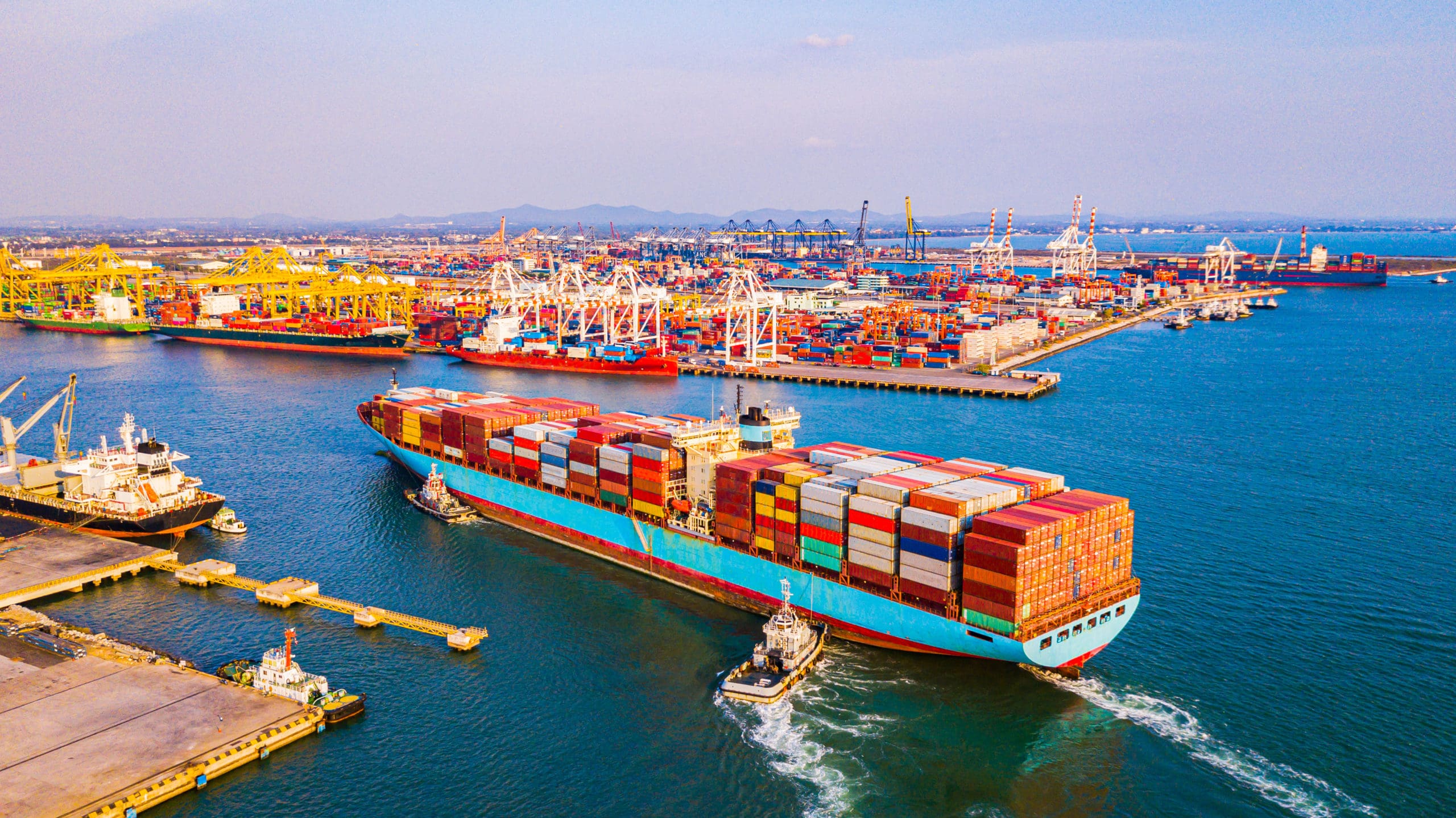Supply Chain Shipping and Logistics Container ship navigating busy port with cargo containers and cranes.