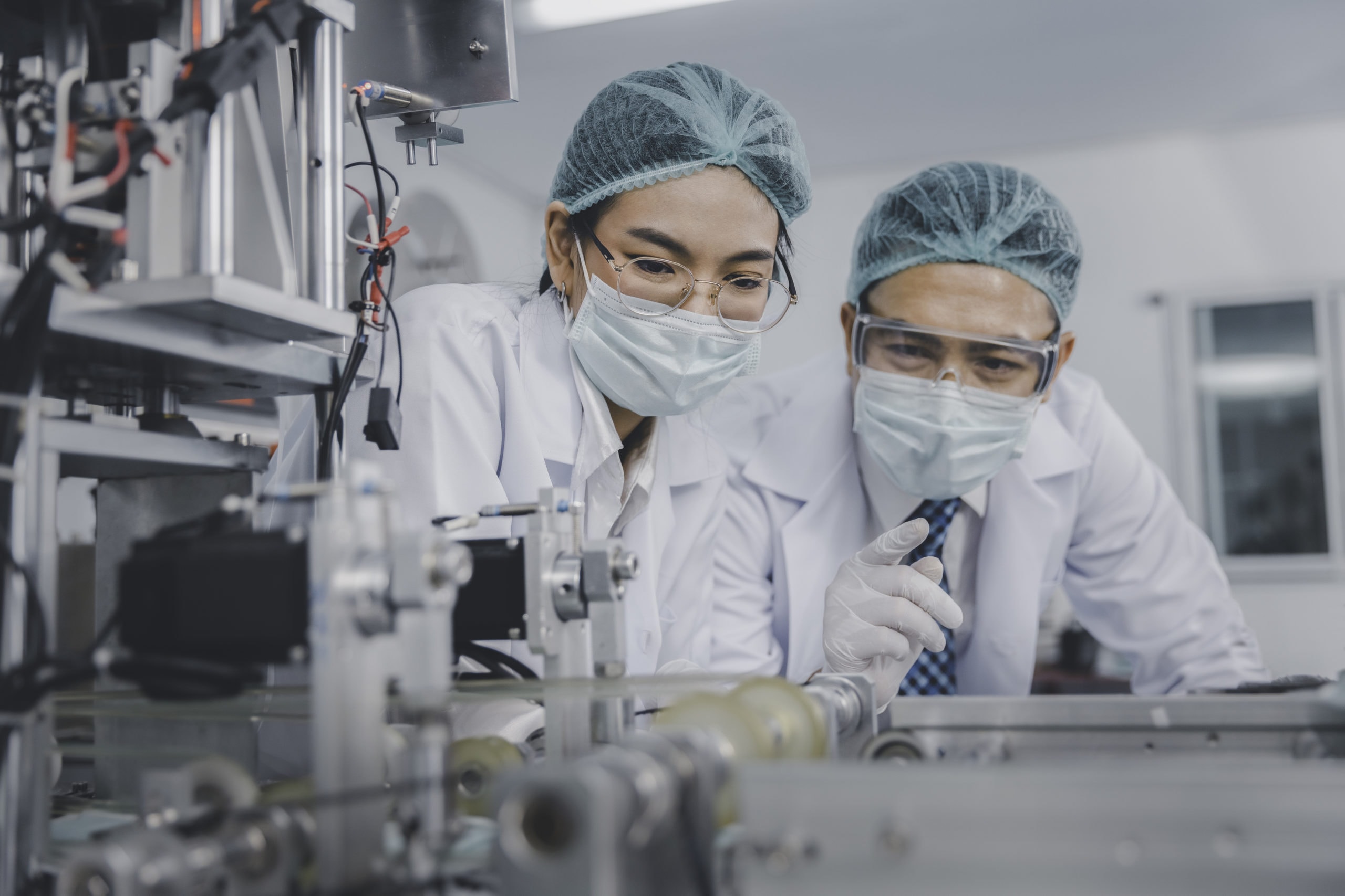 Innovative Scientific Research Scientists in lab wearing masks working on high-tech equipment.