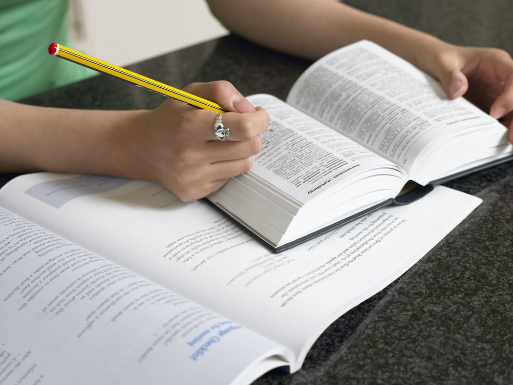 Effective lead generation strategies for business growth. Person studying business strategies with open books and a pencil.