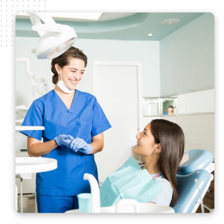 Automator-Service-Providers-Img A dentist in blue scrubs and gloves smiles while talking to a patient sitting in a dental chair, in a bright and modern dental office powered by the best CRM software for seamless patient management.